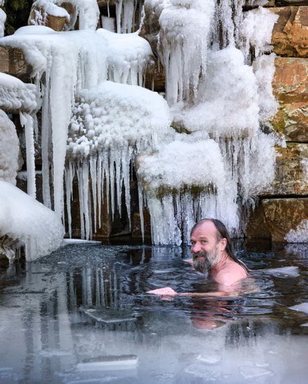 Wim Hof sitting in an icy pool beneath a wall of icicles
